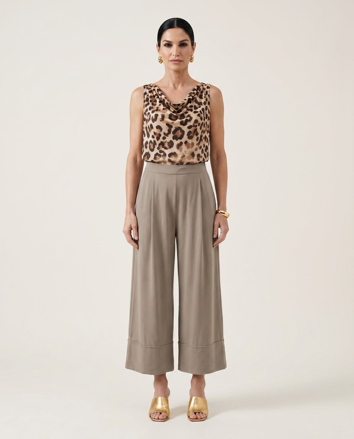 Woman wearing a leopard print top and beige wide-leg pants on a white background